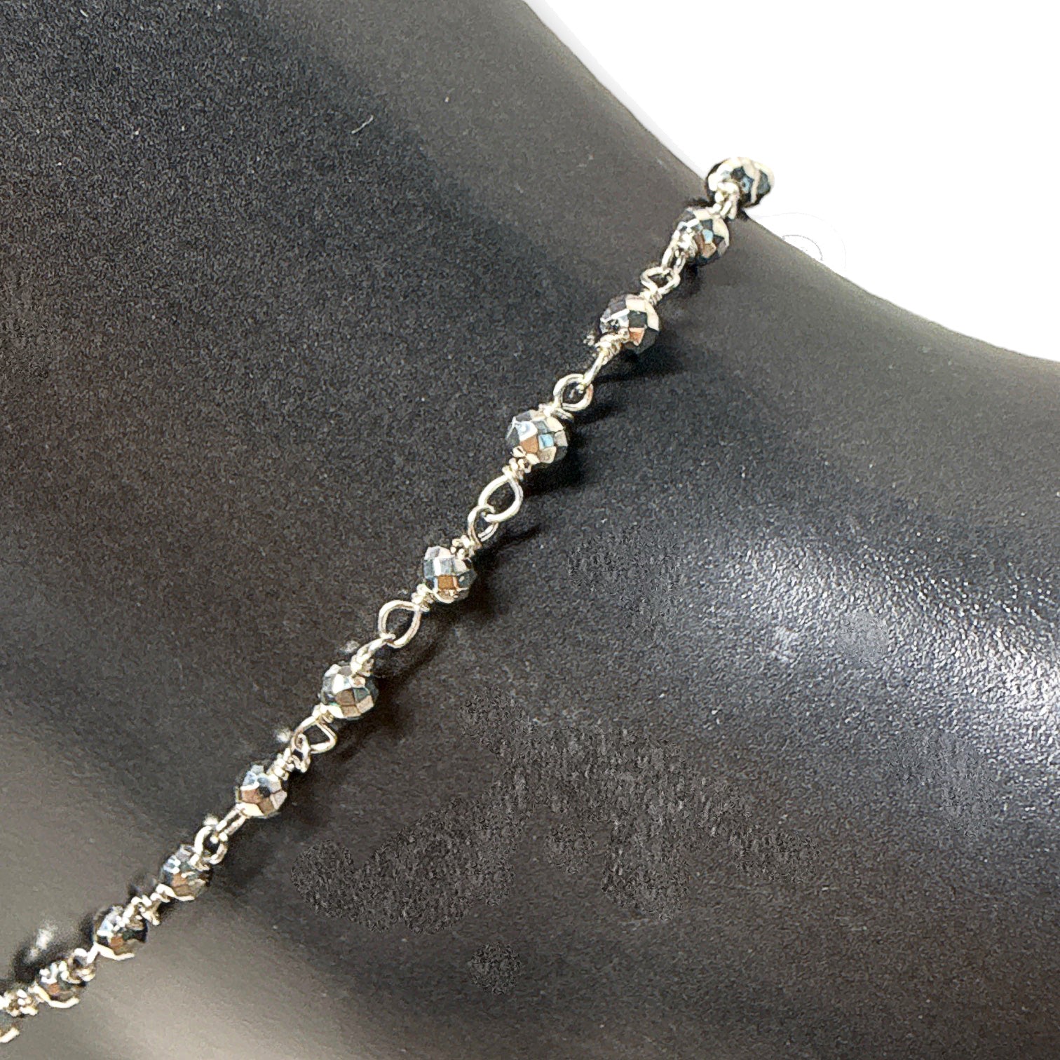 Close up shot of silver bead anklet on a black mannequin